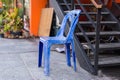 Grungy retro damaged plastic blue chair in the street