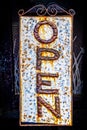 Grungy rusty cracked metal vertical retro open sign hanging in wire frame against dark background Royalty Free Stock Photo