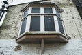 Grungy view of a boarded up bay window shown on a derelict town home.