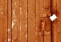 Grungy wooden door with lock in orange tone Royalty Free Stock Photo