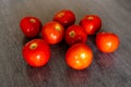 A gruop of bright red fresh tomatoes on the wooden table of a kitchen