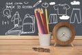 Gruop of pound coins, colour pencils in white pot and wooden clock on wooden table with hand drawing on black broad, Back to schoo