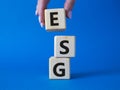 GSG - Environmental, Social and Governance symbol. Concept word GSG on wooden cubes. Businessman hand. Beautiful blue background.