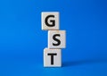 GST - Goods and Services Tax symbol. Concept word GST on wooden cubes. Beautiful blue background. Business and GST concept. Copy Royalty Free Stock Photo