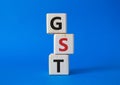 GST - Goods and Services Tax symbol. Concept word GST on wooden cubes. Beautiful blue background. Business and GST concept. Copy Royalty Free Stock Photo