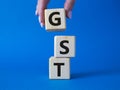 GST - Goods and Services Tax symbol. Concept word GST on wooden cubes. Businessman hand. Beautiful blue background. Business and Royalty Free Stock Photo