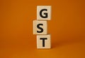 GST - Goods and Services Tax symbol. Concept word GST on wooden cubes. Beautiful orange background. Business and GST concept. Copy Royalty Free Stock Photo