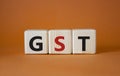 GST - Goods and Services Tax symbol. Concept word GST on wooden cubes. Beautiful orange background. Business and GST concept. Copy Royalty Free Stock Photo