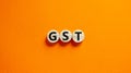 GST, goods and services tax symbol. Concept words GST, goods and services tax on wooden circles on a beautiful orange background. Royalty Free Stock Photo