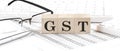 GST - Goods and Services Tax written on wooden cube with keyboard , calculator, chart,glasses.Business concept Royalty Free Stock Photo