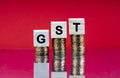 GST TAX Concept with wooden block on stacked coins and red background Royalty Free Stock Photo