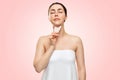 Gua Sha Massage. A young woman in a bath towel, closing her eyes, makes a guasha massage in the area of the chin and neck. Pink Royalty Free Stock Photo