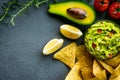 Guacamole bowl with ingredients and tortilla chips on a stone table. Top view image. Copyspace for your text. Royalty Free Stock Photo