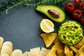 Guacamole bowl with ingredients and tortilla different tipes of chips on a stone table. Top view image. Copyspace for Royalty Free Stock Photo