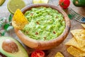 Guacamole, guacamole ingredients and chips on wooden background