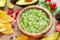 Guacamole, guacamole ingredients and chips on wooden background