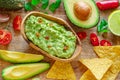 Guacamole, guacamole ingredients and chips on wooden background. Flat lay