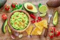 Guacamole, guacamole ingredients and chips on wooden background. Flat lay