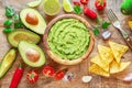 Guacamole, guacamole ingredients and chips on wooden background. Flat lay Royalty Free Stock Photo