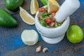 Guacamole - latin american sauce and ingredients avocado, tomatoes, onion, lemon, garlic, lime on blue wooden background. Royalty Free Stock Photo