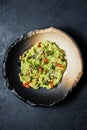 Guacamole with roasted peanuts, black background, top view.