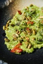 Guacamole with roasted peanuts, black background, top view.