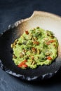 Guacamole with roasted peanuts, black background, top view.