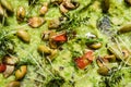 Guacamole with roasted peanuts, black background, top view.