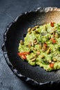 Guacamole with roasted peanuts, black background, top view.