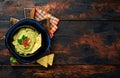 Guacamole. Traditional latinamerican Mexican dip sauce in a black bowl with avocado and ingredients and corn nachos. Avocado