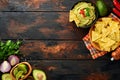 Guacamole. Traditional latinamerican Mexican dip sauce in a black bowl with avocado and ingredients and corn nachos. Avocado