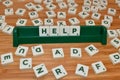 Help word made up of letter tiles surrounded by letters. Woden Table Royalty Free Stock Photo