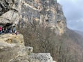 Guamka, Russia april 17, 2021: Tourists on huge cliff with spectacular view of nature. Group of people on high rock in