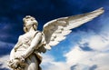 Guardian angel white marble sculpture with open long wings across frame against bright sunny dark blue sky with white clouds.