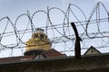 Guarding tower behind barbed wire fence around prison walls