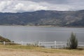 Guatavita lake summer scene with wooden fence, green mountains and blue sky