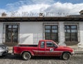 Old red pickup truck in front of colonial style house with rod iron bars on windows Royalty Free Stock Photo