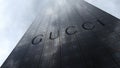 Gucci logo on a skyscraper facade reflecting clouds. Editorial 3D rendering