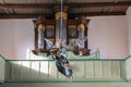 Gudow, Germany, November 13, 2020: Baroque wooden baptism angel hanging on the ceiling in front of the organ in the St. Mary`s