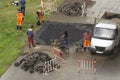 Guest workers in overalls perform road works on laying asphalt