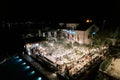 Guests sit at festive tables in the courtyard of the Adriatica Hotel at night under the light of garlands of light bulbs