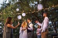 Guests with smartphones taking photo of bride and groom at wedding reception outside.