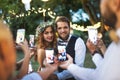 Guests with smartphones taking photo of bride and groom at wedding reception outside. Royalty Free Stock Photo