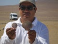 Guide demonstrates mollusk shells forming relict surface of Atacama Desert in Peru, South America