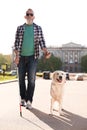 Guide dog helping blind person with long cane walking