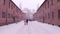 Guided tour to Auschwitz Birkenau, German Nazi concentration and extermination camp. Brick buildings in falling snow Royalty Free Stock Photo