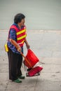 Woman in security vest is street sweeper along Li River, Guilin, China