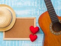 The guitar, board with red heart and hat on blue wooden texture