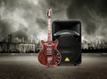 Guitar and column speaker on view of city in stormy sky Royalty Free Stock Photo