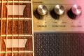 Guitar fretboard and fret marker detail, blurred old amplifier knobs in the background